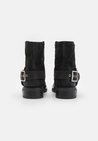 Botas de tobillo de ante negro con una textura suave, que presentan un detalle de hebilla en el lateral y tacones gruesos y resistentes. Doble costura en la parte trasera.