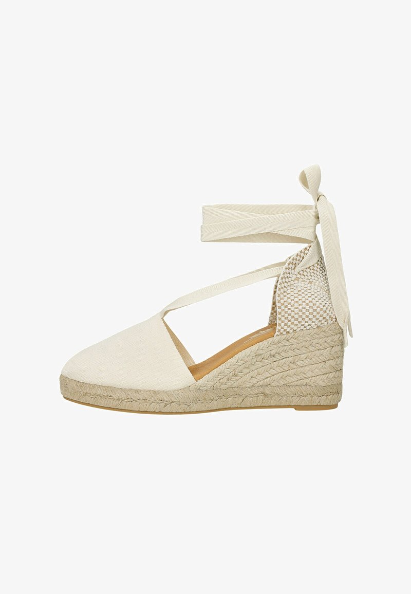 Espadrille compensée en toile blanche, avec un talon tissé texturé et des liens à la cheville. Tissu lisse avec un bout arrondi et des côtés ouverts.