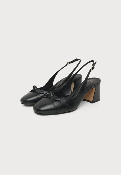 Ζευγάρι μαύρες δερμάτινες γόβες slingback με τετράγωνη μύτη, χοντρό τακούνι και μικρό διακοσμητικό φιόγκο μπροστά, εμφανίζεται σε λευκό φόντο.