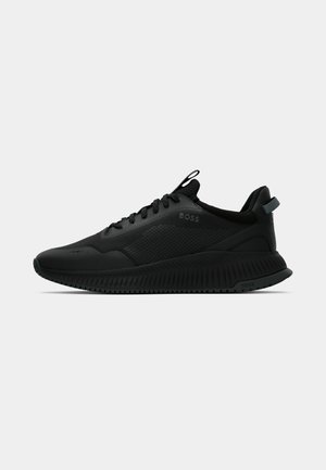Black athletic shoes with a smooth, textured upper, featuring laces, a padded collar, and a ridged rubber sole for traction.