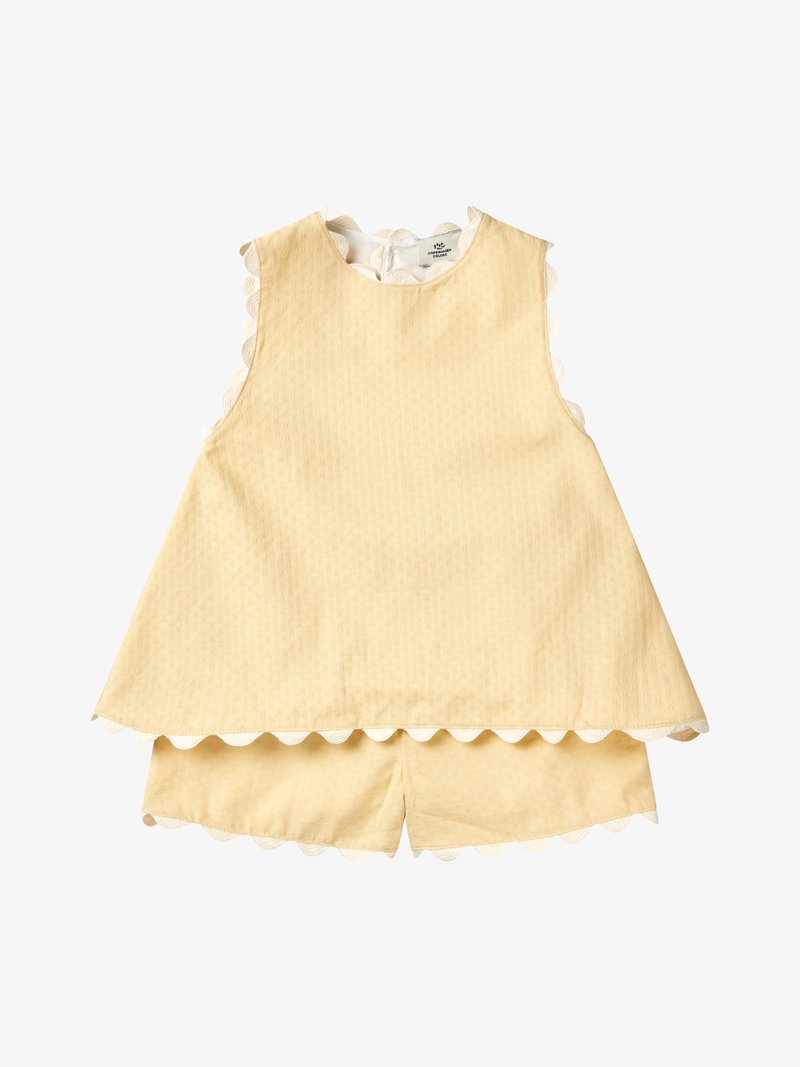 Abito smanicato da bambino in giallo pallido con pantaloncini abbinati, rifiniti con bordo in pizzo bianco smerlato lungo i bordi.