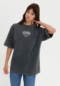 Gray oversized T-shirt in soft fabric featuring a vintage-style print with "San Diego" in white. Casual fit with short sleeves and round neck.