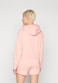 Rosa hettegenser med hette, med en strukturert krage og ribbestrikket hem, kombinert med matchende shorts. Mykt stoff, avslappet passform.