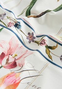 Tissu blanc avec des imprimés floraux comprenant des tulipes roses ainsi que des fleurs bleues et violettes, bordé de rayures bleues et roses et texte en écriture cursive.