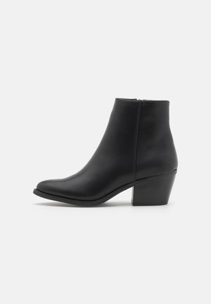 Black leather ankle boot with a pointed toe, side zipper, and a chunky heel. Smooth texture and minimal design.