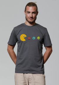 Grijze katoenen t-shirt met een gele Pac-Man graphic en vier kleurrijke ronde gezichten met verschillende uitdrukkingen op de voorkant.