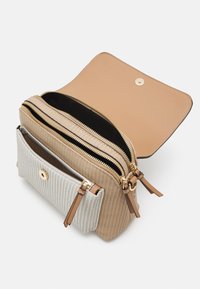 Sac à main tissé beige avec un rabat en cuir lisse brun clair, deux compartiments zippés et une poche avant, ornés de quincaillerie et d'accents dorés.