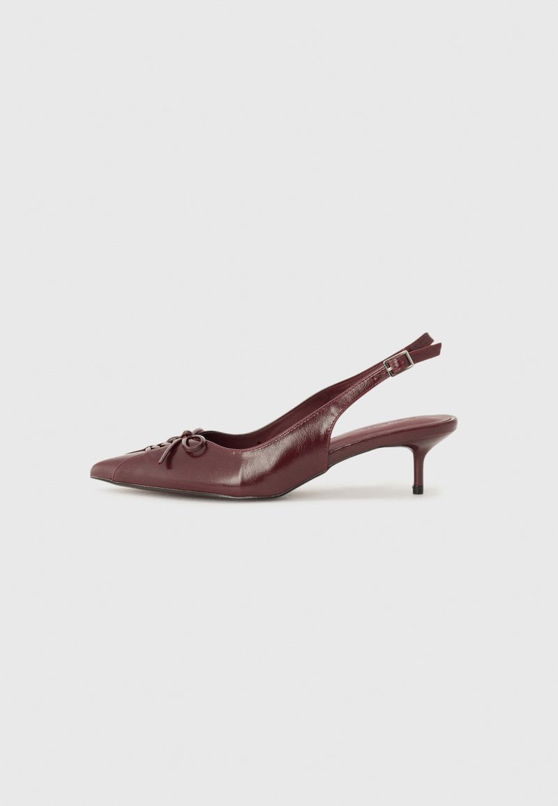 Burgundy-nahkainen slingback-korkokenkä, jossa on teräväkärkinen muotoilu, säädettävä hihna ja koristeellinen perhonen etuosassa. Korkeus 7,5 cm.