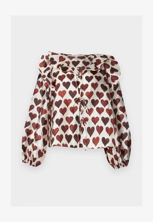 Blusa de manga larga, brillante, con patrones de corazones rojos, cuello con volantes y detalles de lazo delantero sobre fondo blanco.