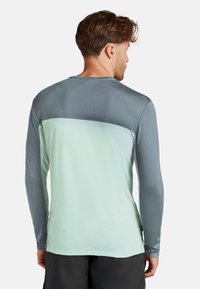 Långärmad skjorta med gradientdesign, mörkgrå överdel, ljus mintgrön underdel och slät textur. Bakomifrån syns enkel sömnad.