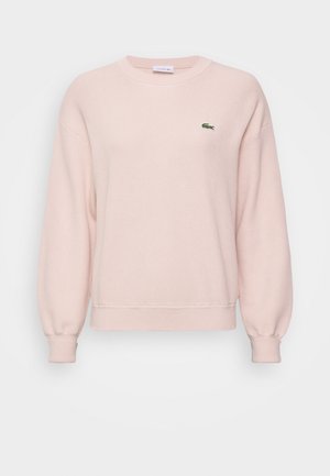 Lichtroze sweatshirt gemaakt van zachte stof, met een ronde hals, verlaagde schouders en een groen geborduurd logo op de linkerkant van de borst.