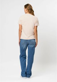 Lichtroze T-shirt met korte mouwen en loszittende blauwe spijkerbroek. Het shirt heeft een ronde halslijn en de jeans hebben achterzakken en een rechte snit.
