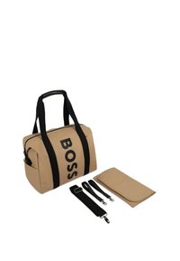 Borsa a viaggio BOSS beige con manici neri, accompagnata da una tracolla nera regolabile, due piccoli ganci neri e un tappetino pieghevole beige.