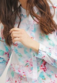 Bloemmotief, lichtgewicht blouse met een witte basis en blauwe, roze en groene tinten. Het heeft een gewone kraag en knoopmanchetten.