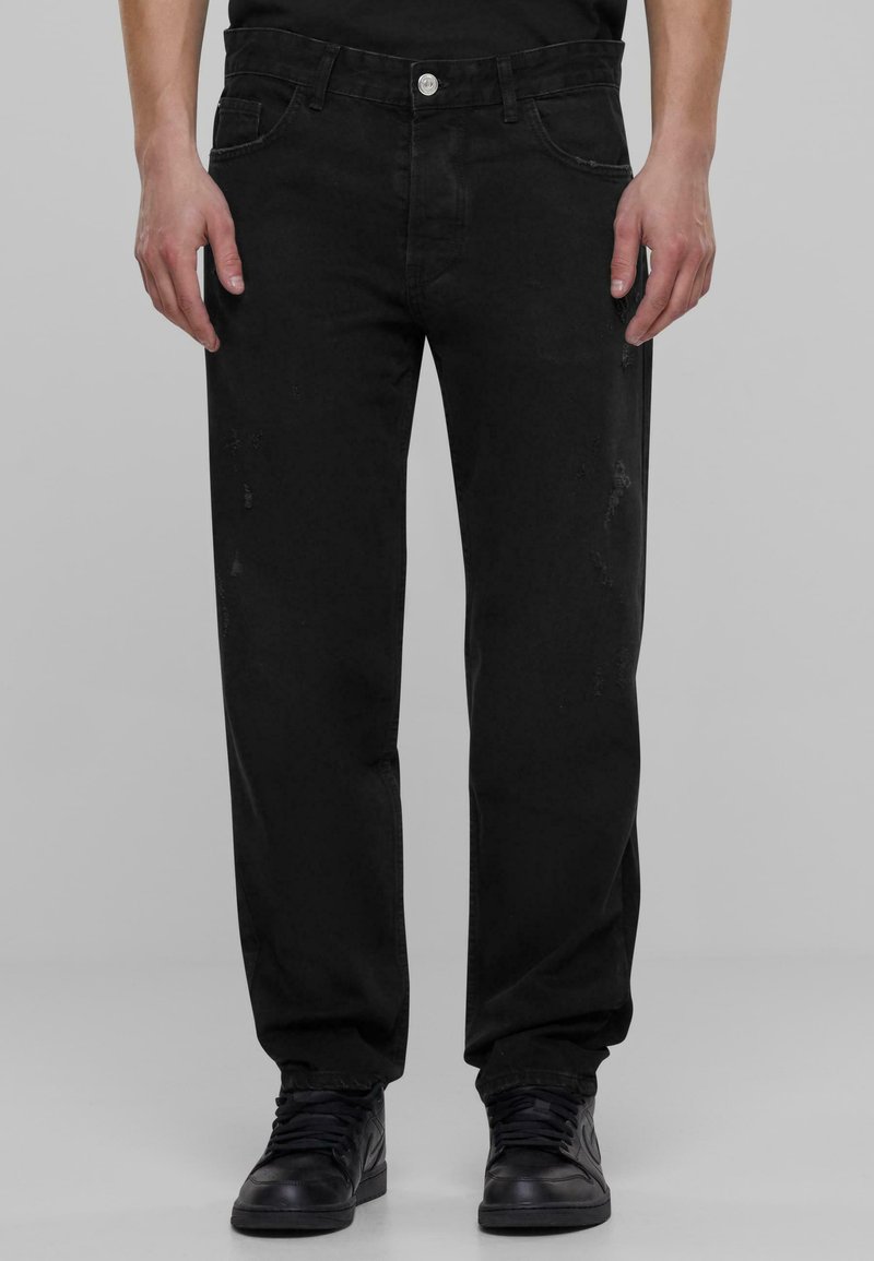 Črne denim hlače ravnega kroja, s klasičnim dizajnom petih žepov, gumbnim zapiranjem in subtilnimi obrabljenimi detajli vzdolž nog.
