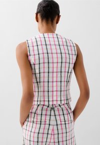 Top aderente senza maniche realizzato in tessuto leggero, caratterizzato da un motivo a quadri multicolori in bianco, nero, rosa e beige. Design cropped con una cucitura sul retro.