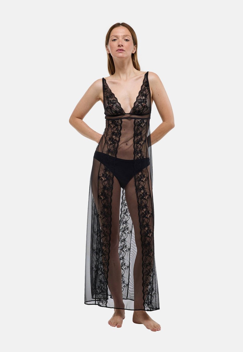 Nuisette en dentelle noire avec un décolleté en V profond, tissu transparent, motif floral sur les bords et longueur maxi. Comprend un string noir assorti.