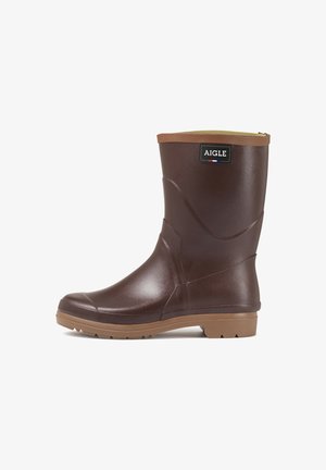 Botte de pluie en caoutchouc marron avec une finition lisse, bout arrondi et une accentuation beige sur le haut. Semelle texturée pour une meilleure adhérence. Logo de la marque affiché.