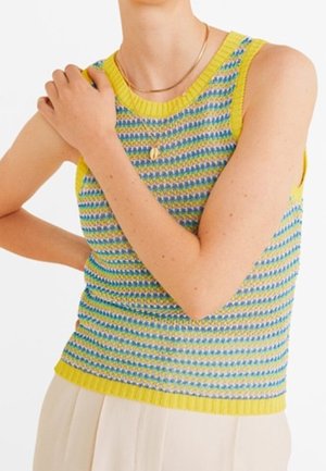 Haut sans manches en tricot avec bordure jaune, présentant des rayures horizontales bleues et vertes, porté avec un collier en or et un pantalon de couleur claire.
