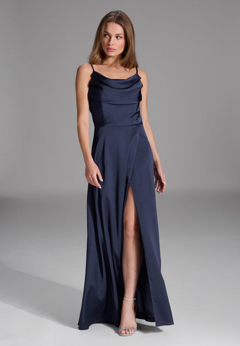 Abito da sera in satin navy con scollatura a cowl, spalline sottili e spacco frontale, con una silhouette fluttuante e una texture liscia.
