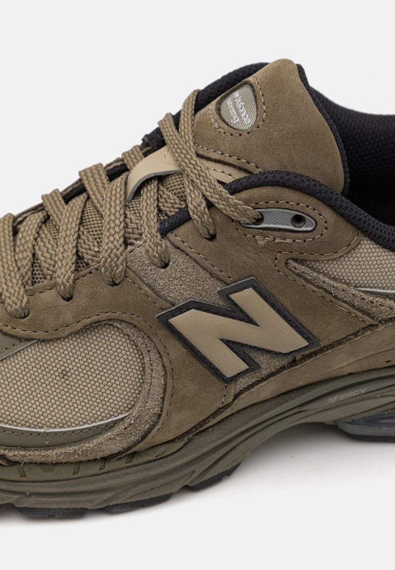 Baskets en suède marron et en maille avec un col rembourré, des accents texturés, des lacets épais et un logo 'N' proéminent en gris foncé.
