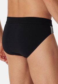 Sorte bomuldsunderbukser med en glat tekstur, klassisk højskåret design og en kontrastgrå accent på siden.