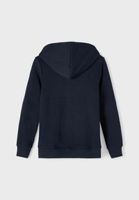 Sweat à capuche bleu marine avec une texture de tissu doux, des manches longues et des bords côtelés au niveau des poignets et de l'ourlet. Présente un détail de couture verticale au dos.
