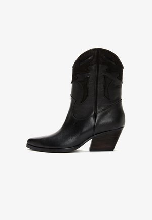 Mustasta nahasta valmistettu puolipitkä cowboy-saapas, jossa on teksturoitu päälliosa, terävä kärki ja kalteva pinottu puukorko valkoisella taustalla.