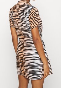 Šaty s krátkým rukávem a vypasovaným střihem, zdobené horizontálním vzorem zebřích pruhů v černé a oranžové barvě. Vyrobené z hladkého, elastického materiálu.