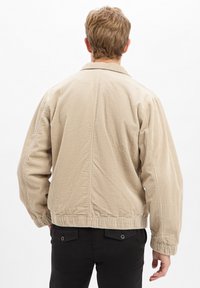 Beige corduroy jacket met een relaxed fit, ribbelstructuur en elastische zoom, met een eenvoudige kraag en ingestopte naden.