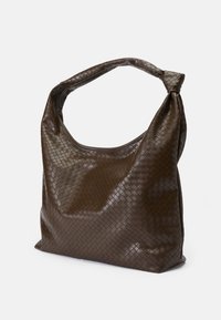 Barna, fényes felületű szőtt táska csomózott fogantyúval. Puha, lekerekített formájú, texturált felületű, kockás mintázattal.