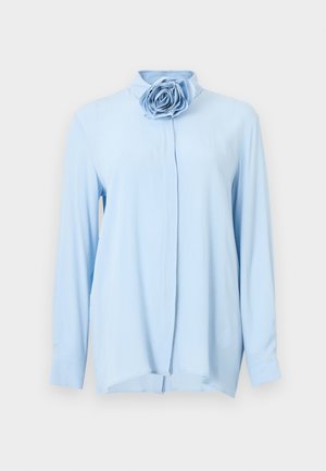 Light blue long-sleeve shirt made of soft fabric, featuring a high collar and a large rose appliqué on the front. Straight hem with side slits.