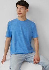 Korte mouwen shirt in lichtblauw, gemaakt van textuurstof met een ronde halsontwerp. Draagt met lichtgewassen denim jeans.