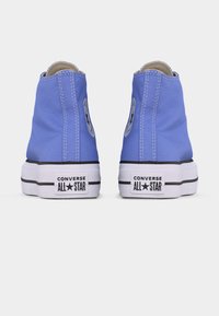 Ζευγάρι μπλε ψηλά sneakers Converse All Star, εμφανιζόμενα από την πίσω πλευρά, με λευκές σόλες και μαύρο λογότυπο της μάρκας στη φτέρνα.