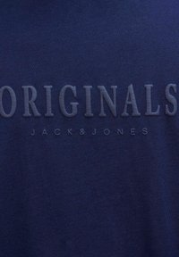 Tmavě modré bavlněné tričko s embosovaným textem "ORIGINALS" a "JACK & JONES" v světlejším odstínu, hladká textura, krátké rukávy.