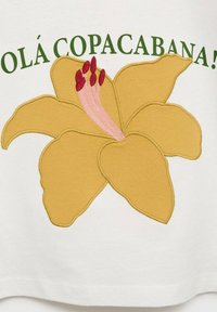 Valkoinen vaate, jossa on suuri keltainen kukkakuosi, jossa on vaaleanpunaisia ja punaisia yksityiskohtia. Teksti "OLÁ COPACABANA!" on vihreällä kukan yläpuolella.