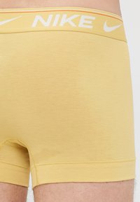 Nike herenboxershorts in een lichtgele tint, met een gelogodeerde tailleband en een gladde stof. Het ontwerp bevat een aansluitende stijl met korte pijpen.