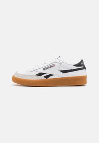 White leather sneakers with black accents and suede toe cap. Features a gum rubber sole and Reebok branding on the side and heel.