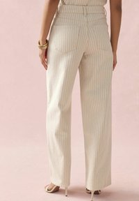 Pantalones de corte ancho hechos de una tela ligera con rayas verticales en crema y rojo. Presentan dos bolsillos traseros y un diseño de cintura alta.