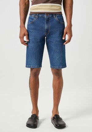 Denim shorts in dark blue, knee-length with a straight cut. Five pockets, belt loops, and visible stitching on edges, worn with black shoes.