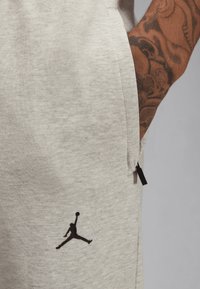 Svijetlosive trenirke izrađene od mekog materijala, sa crnim Jumpman logotipom na lijevom bedru i detaljem sa bočnim patentnim zatvaračem.