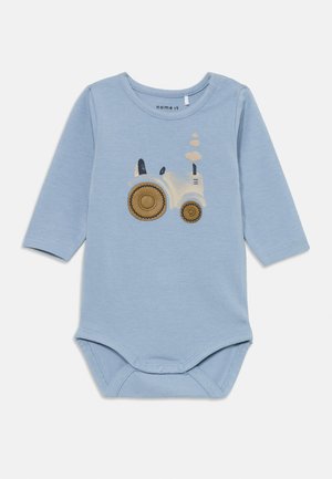 Hellesblaues Langarm-Bodysuit mit einem Traktor-Design in Weiß und Braun, ausgestattet mit Druckknöpfen im unteren Bereich und einem runden Ausschnitt.