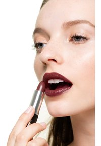 Mörk burgundyröd läppstift med ett metalliskt silverrör, som appliceras på läpparna. Sl�ät textur, med en lätt lyster på läpparna och subtila fräknar på huden.