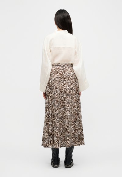 Λευκό, φαρδύ πουκάμισο με μακριά μανίκια συνδυασμένο με καφέ μακρύ φούστα με λεοπάρ σχέδιο. Μαύρα μποτάκια αστραγάλου με ασημένιες λεπτομέρειες.