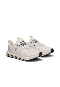 Scarpe sportive bianche con tomaia in rete, caratterizzate da dettagli neri e un design con lacci. La suola presenta un motivo cavo distintivo.
