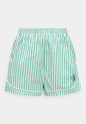 Grønne og hvite shorts med vertikale striper, elastisk midje og liten svart "CK"-logo på nedre høyre ben.