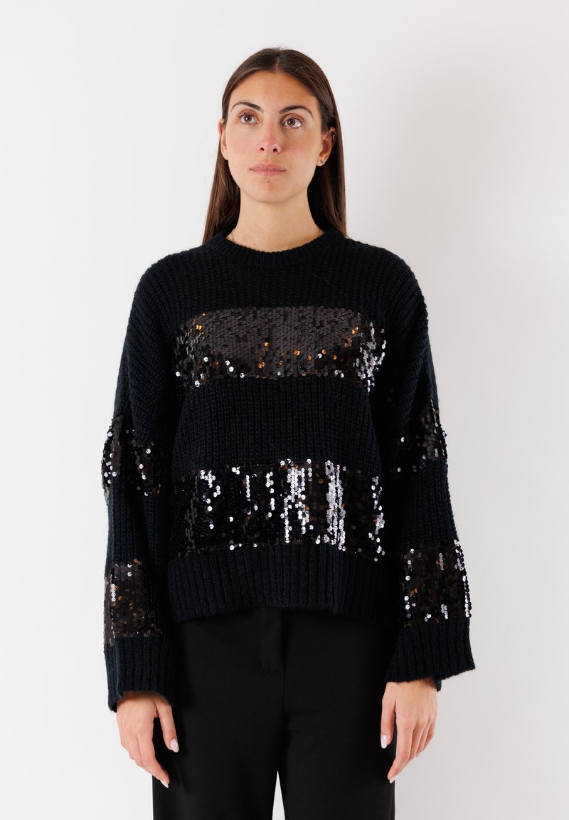 Maglione nero a maglia con strisce di paillettes, caratterizzato da una vestibilità ampia, polsini e orlo a costine. La texture comprende un motivo a maglia prominente.