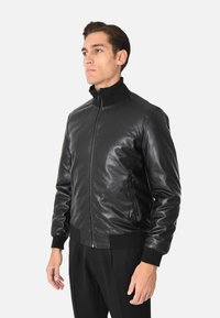 Giubbotto bomber in pelle nera con zip frontale, polsini a costine e colletto alto, dallo stile morbido e dalla vestibilità sagomata.