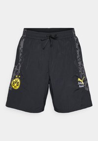 Pantalones cortos deportivos negros con cintura elástica y cordón. Presentan el logo del club en amarillo y gráficos de acento en los lados. Material ligero.