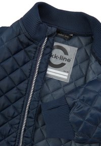 Jachetă din material matlasat de culoare navy cu guler rib pentru o cusătură confortabilă. Prezintă un fermoar argintiu și un eticheta cu marca mikk-line. Textură netedă, design casual.